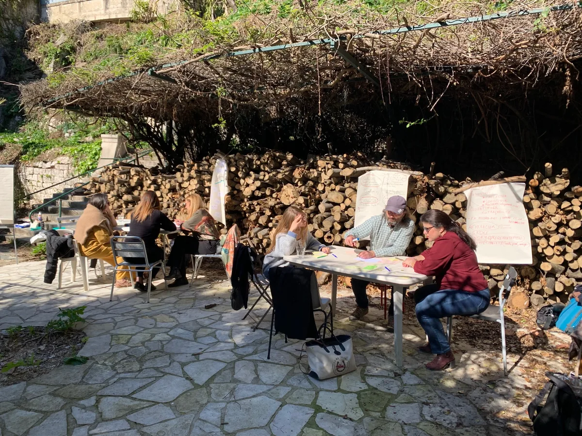 Séance de travail collective en extérieur, autour de tables et de paperboards, sous une treille